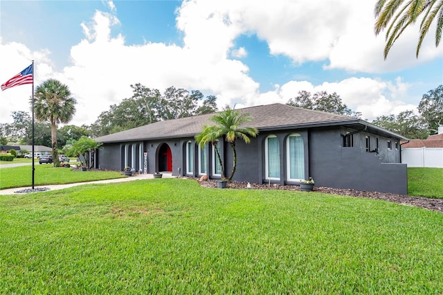 view of front of house featuring fence, a front lawn, and stucco siding