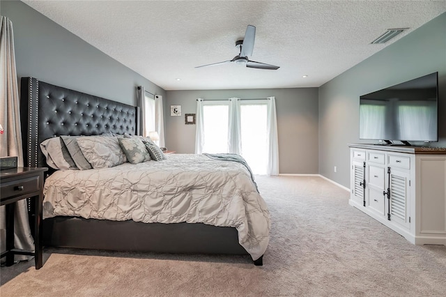 bedroom with a textured ceiling, ceiling fan, visible vents, baseboards, and carpet