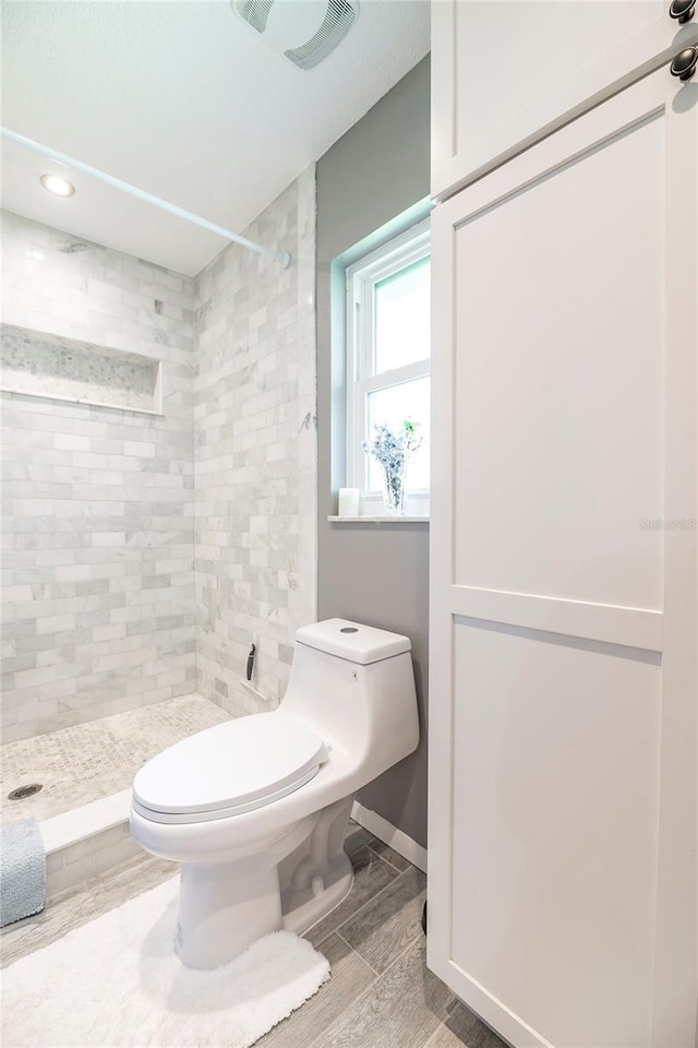 bathroom with toilet, a stall shower, wood tiled floor, and visible vents