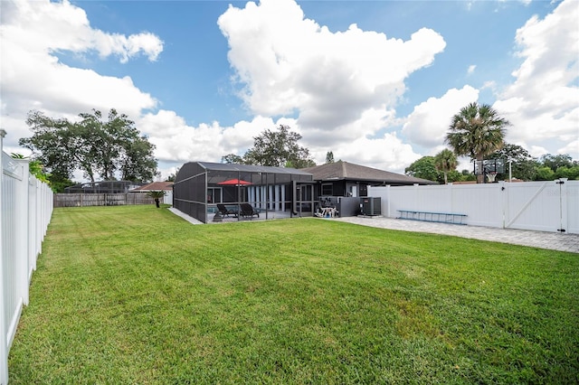 back of property with central air condition unit, glass enclosure, a fenced backyard, and a lawn