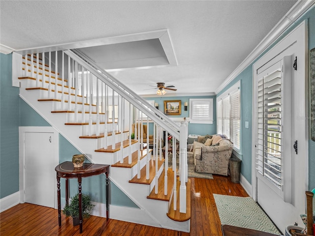 stairs with crown molding, hardwood / wood-style floors, a textured ceiling, and ceiling fan