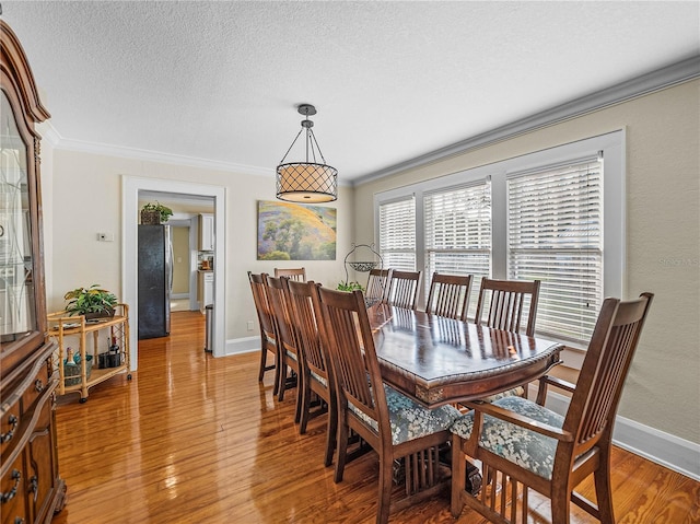 dining space with ornamental molding, hardwood / wood-style floors, and a textured ceiling