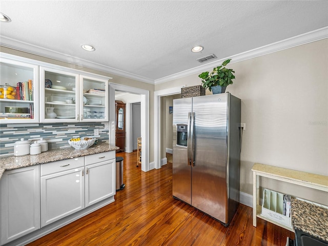 kitchen with crown molding, white cabinetry, backsplash, light stone counters, and stainless steel fridge with ice dispenser