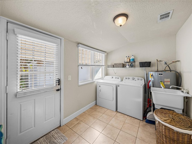 laundry area with a healthy amount of sunlight, sink, light tile patterned floors, and washing machine and clothes dryer