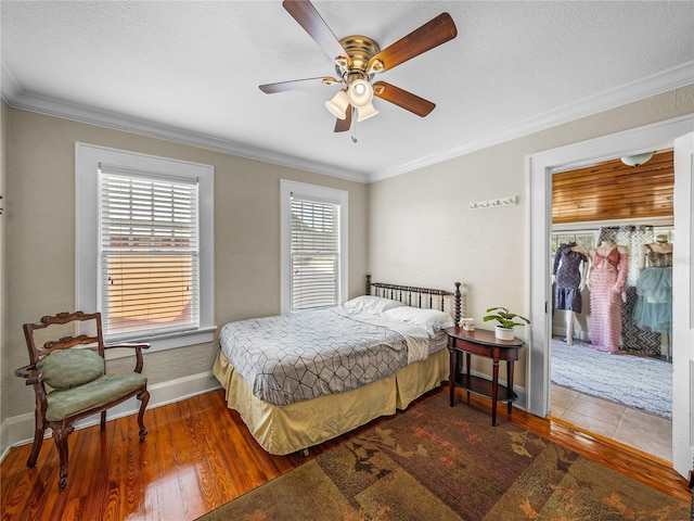 bedroom with hardwood / wood-style flooring, ornamental molding, a textured ceiling, a spacious closet, and a closet