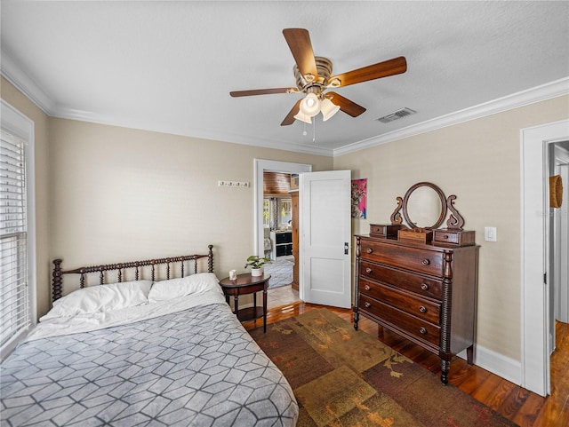 bedroom featuring dark wood-type flooring, ornamental molding, and ceiling fan