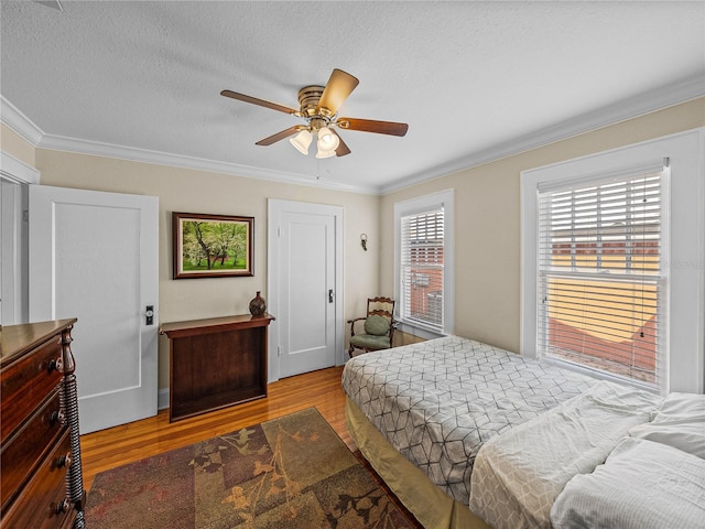 bedroom with ceiling fan, ornamental molding, light hardwood / wood-style flooring, and a textured ceiling