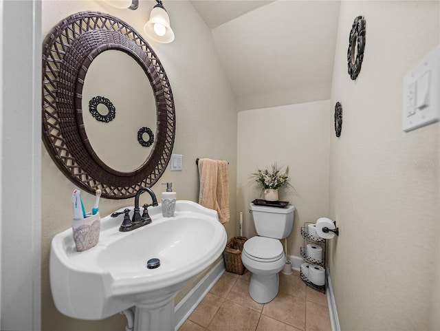 bathroom with tile patterned flooring, vaulted ceiling, sink, and toilet