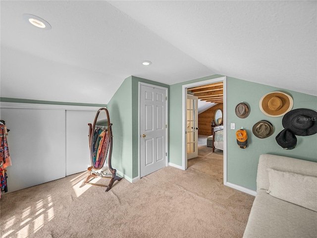 additional living space featuring vaulted ceiling, light colored carpet, and a textured ceiling