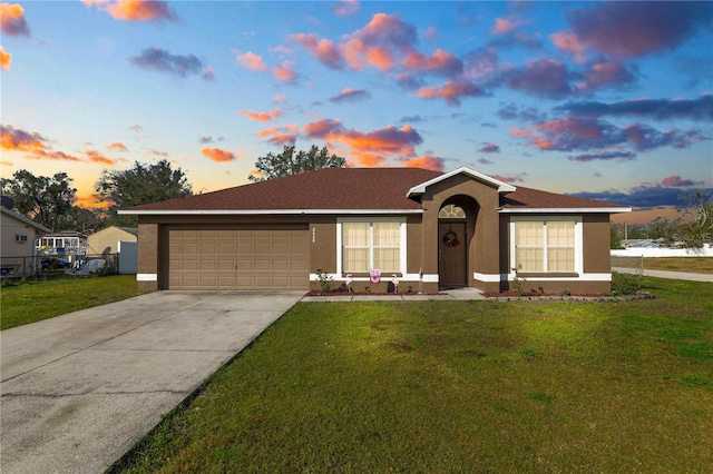 ranch-style home featuring a garage and a yard