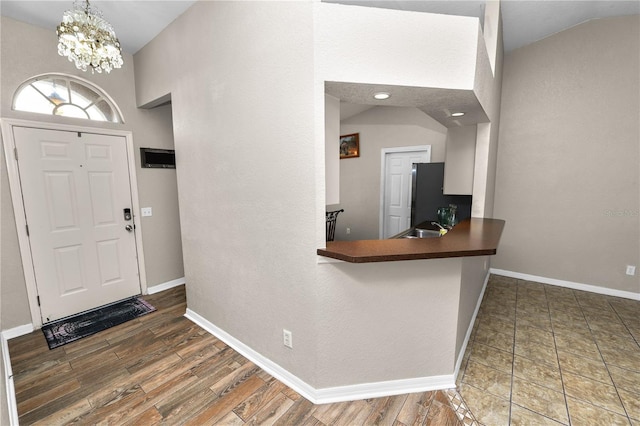 entryway featuring lofted ceiling, sink, dark wood-type flooring, and an inviting chandelier