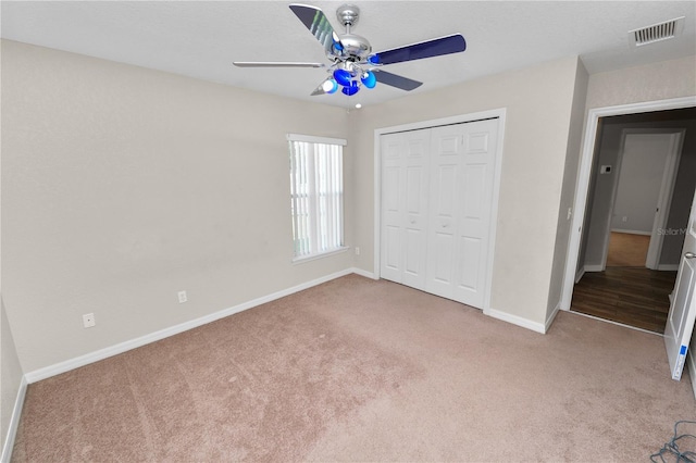 unfurnished bedroom with light colored carpet, a closet, and ceiling fan