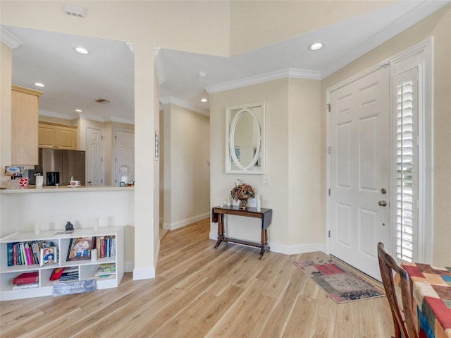 foyer with crown molding and light hardwood / wood-style floors