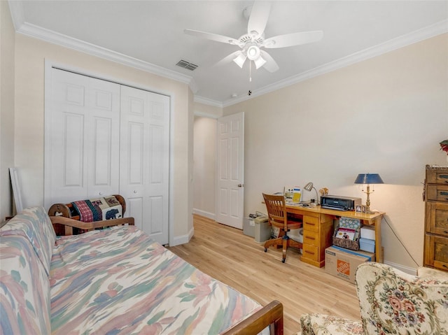 bedroom with ornamental molding, ceiling fan, light wood-type flooring, and a closet