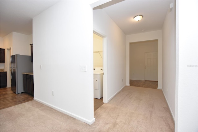 hall featuring washer / clothes dryer and light carpet