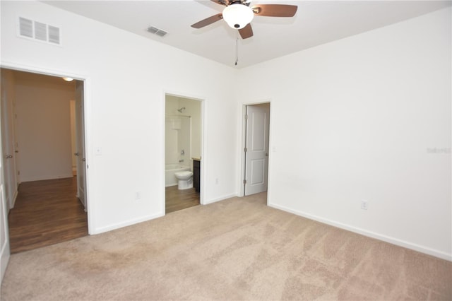 unfurnished bedroom with connected bathroom, light colored carpet, and ceiling fan