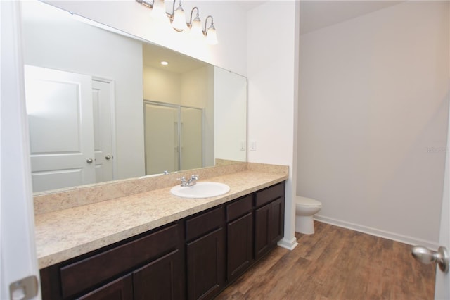 bathroom with a shower with door, vanity, hardwood / wood-style floors, and toilet