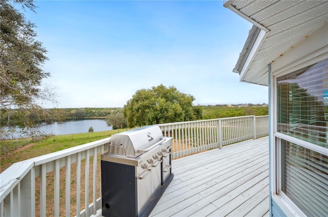 wooden deck with a water view, area for grilling, and a lawn