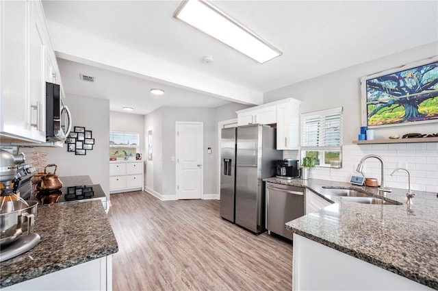 kitchen featuring sink, white cabinetry, dark stone countertops, appliances with stainless steel finishes, and light hardwood / wood-style floors