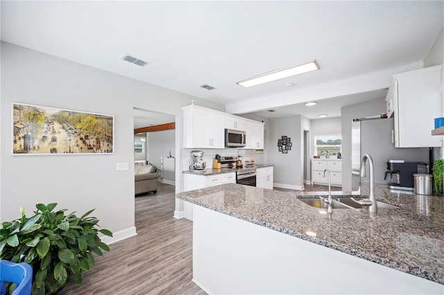 kitchen featuring white cabinetry, sink, kitchen peninsula, stainless steel appliances, and light stone countertops