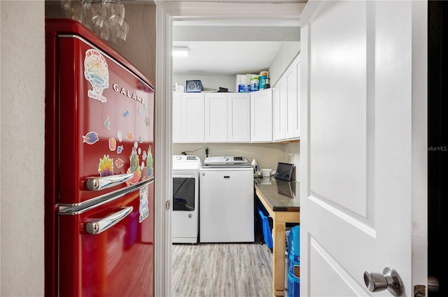 laundry room with cabinets, light hardwood / wood-style flooring, and washer and dryer