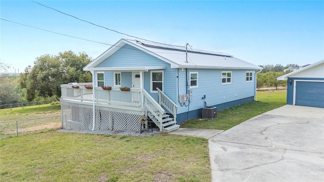 view of front of house featuring a garage, covered porch, a front lawn, and central air condition unit