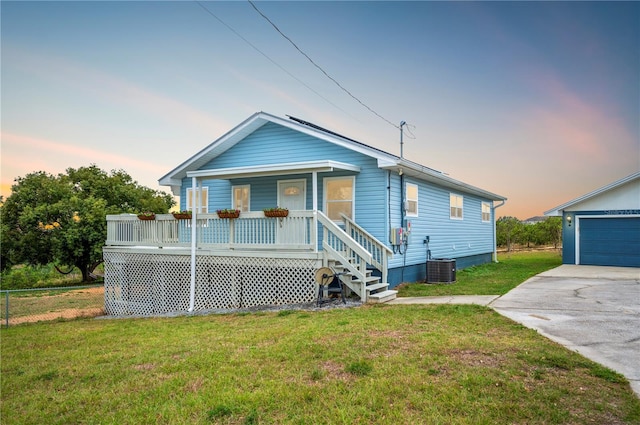 view of front of home with covered porch, a yard, fence, an outdoor structure, and central AC