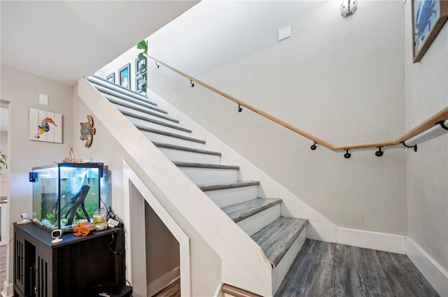 staircase with wood finished floors and baseboards