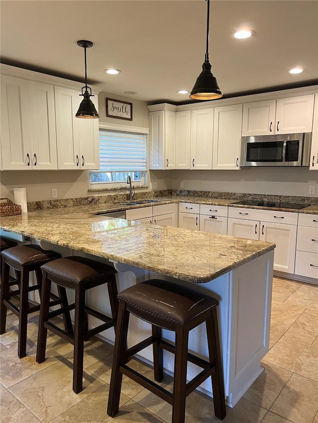 kitchen with sink, white cabinetry, a kitchen breakfast bar, pendant lighting, and black electric stovetop