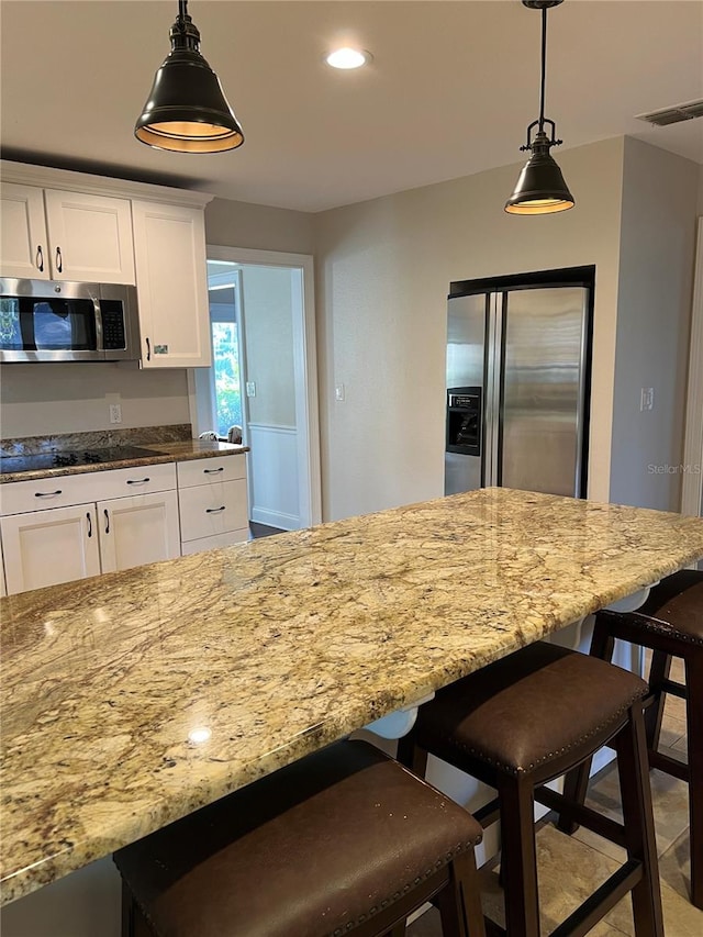 kitchen featuring white cabinetry, hanging light fixtures, stainless steel appliances, and light stone countertops