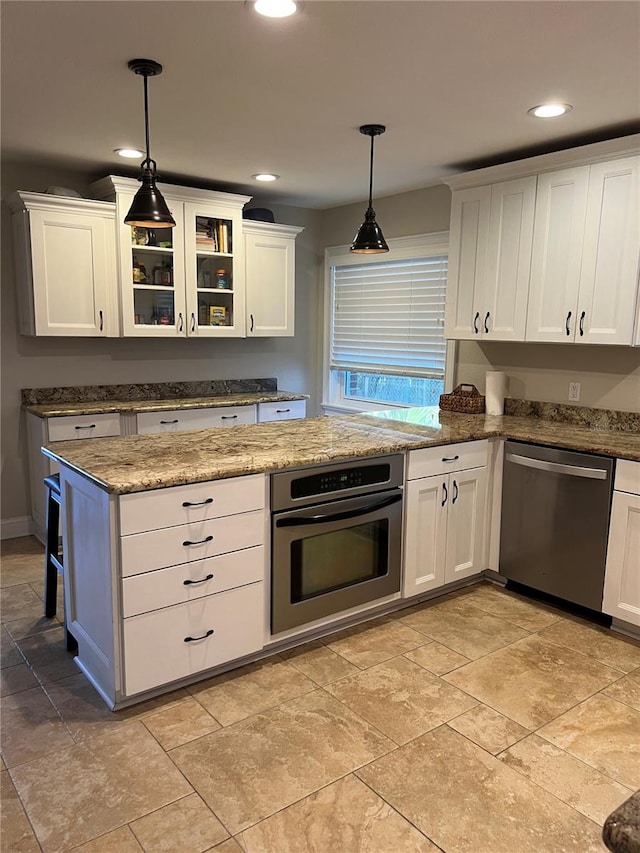 kitchen with light stone counters, appliances with stainless steel finishes, hanging light fixtures, and white cabinets