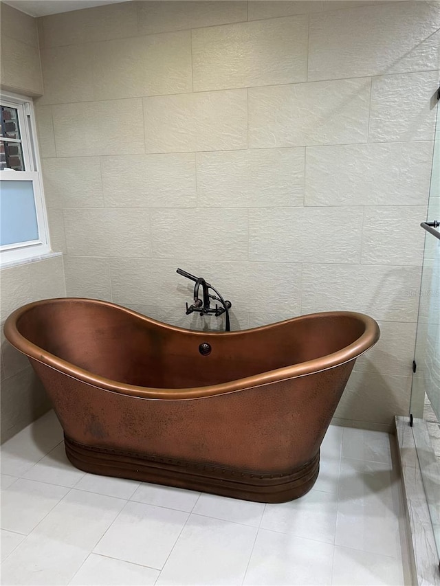 bathroom featuring tile walls, tile patterned floors, and a bathing tub