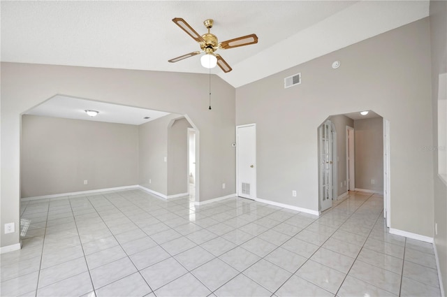 tiled empty room with ceiling fan and high vaulted ceiling