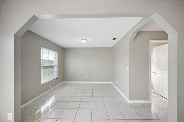 tiled empty room with a textured ceiling