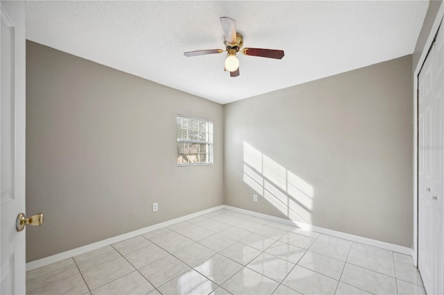 spare room featuring ceiling fan, a textured ceiling, and light tile patterned floors