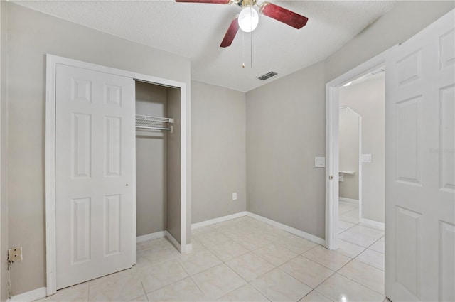 unfurnished bedroom with ceiling fan, light tile patterned floors, a textured ceiling, and a closet