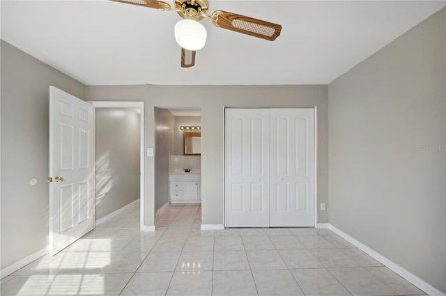 unfurnished bedroom featuring ensuite bathroom, light tile patterned flooring, ceiling fan, and a closet