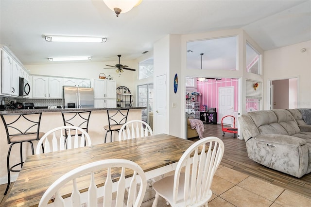 dining room with high vaulted ceiling, light tile patterned floors, and ceiling fan