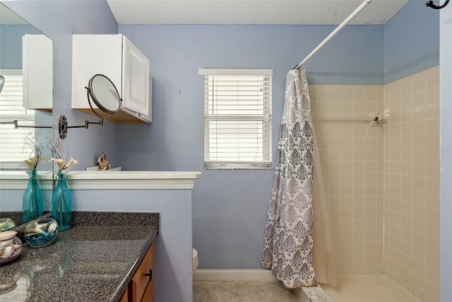 bathroom with tile patterned floors, toilet, a textured ceiling, vanity, and curtained shower