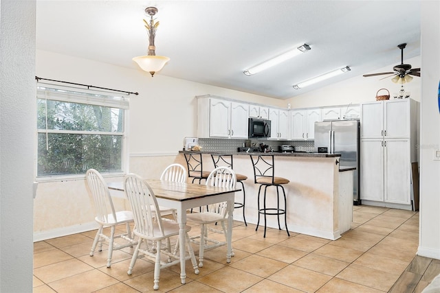 dining area with light tile patterned floors, vaulted ceiling, and ceiling fan