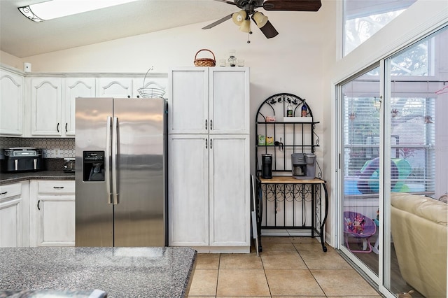 kitchen with lofted ceiling, stainless steel fridge with ice dispenser, white cabinets, and light tile patterned flooring