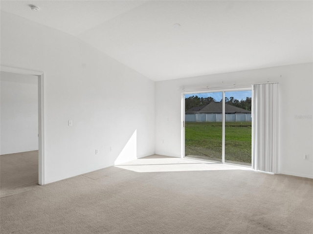 spare room featuring lofted ceiling and light carpet