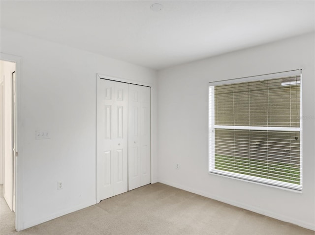 unfurnished bedroom featuring light carpet and a closet