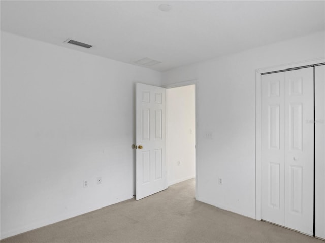 unfurnished bedroom featuring light colored carpet and a closet