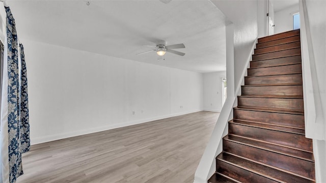 stairs with hardwood / wood-style flooring and ceiling fan