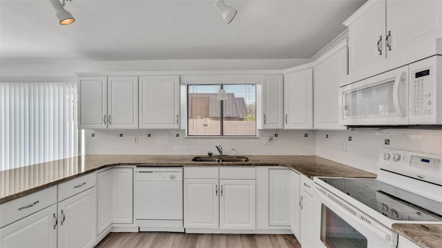 kitchen with sink, white cabinets, white appliances, and dark stone counters