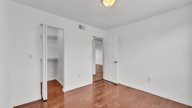 unfurnished bedroom featuring a spacious closet, wood-type flooring, and a closet