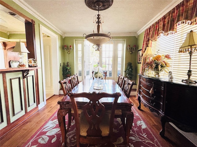 dining room featuring ornamental molding, wood-type flooring, and a textured ceiling