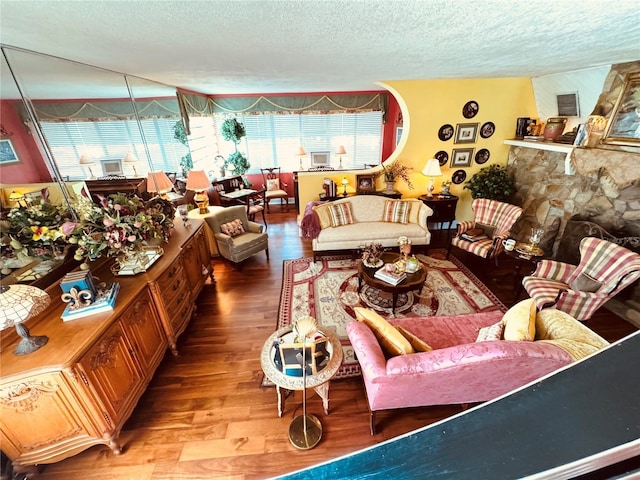 living room featuring a stone fireplace, hardwood / wood-style floors, and a textured ceiling