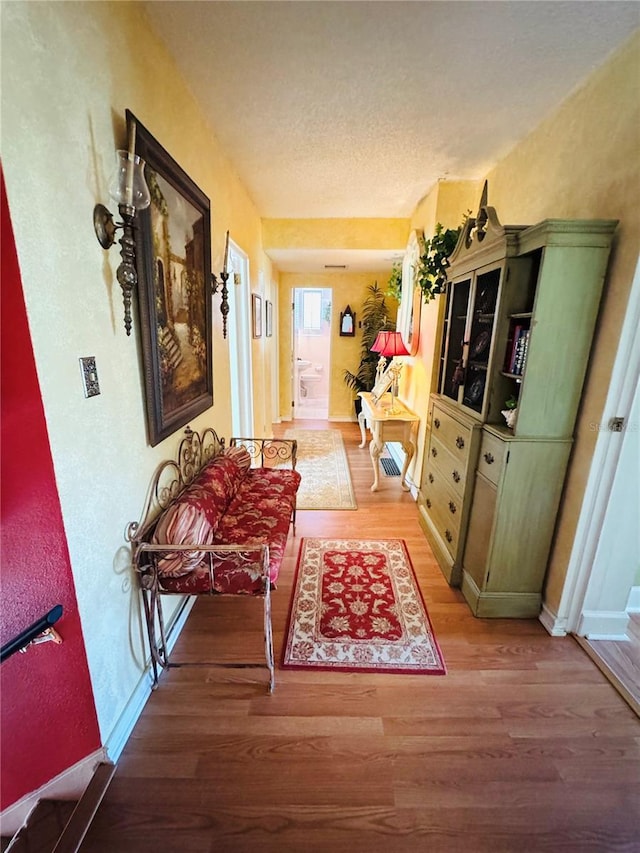 corridor with hardwood / wood-style flooring and a textured ceiling